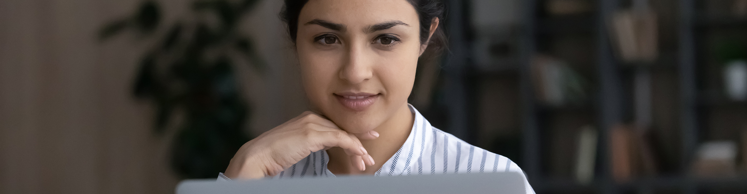 Mujer joven leyendo atentamente un mensaje en el monitor
